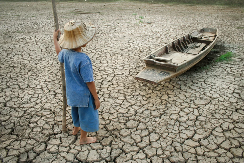 NIÑO AL LADO DE UNA BARCA DE MADERA CON EL SUELO AGRIETADO POR LA SEQUIA
Brasil